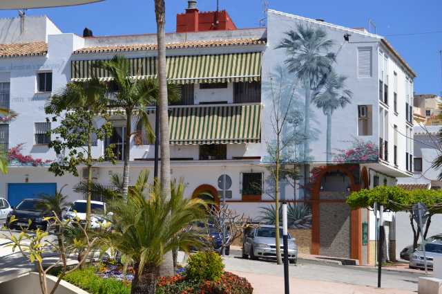 Imagen de un mural en un edificio con palmeras pintadas